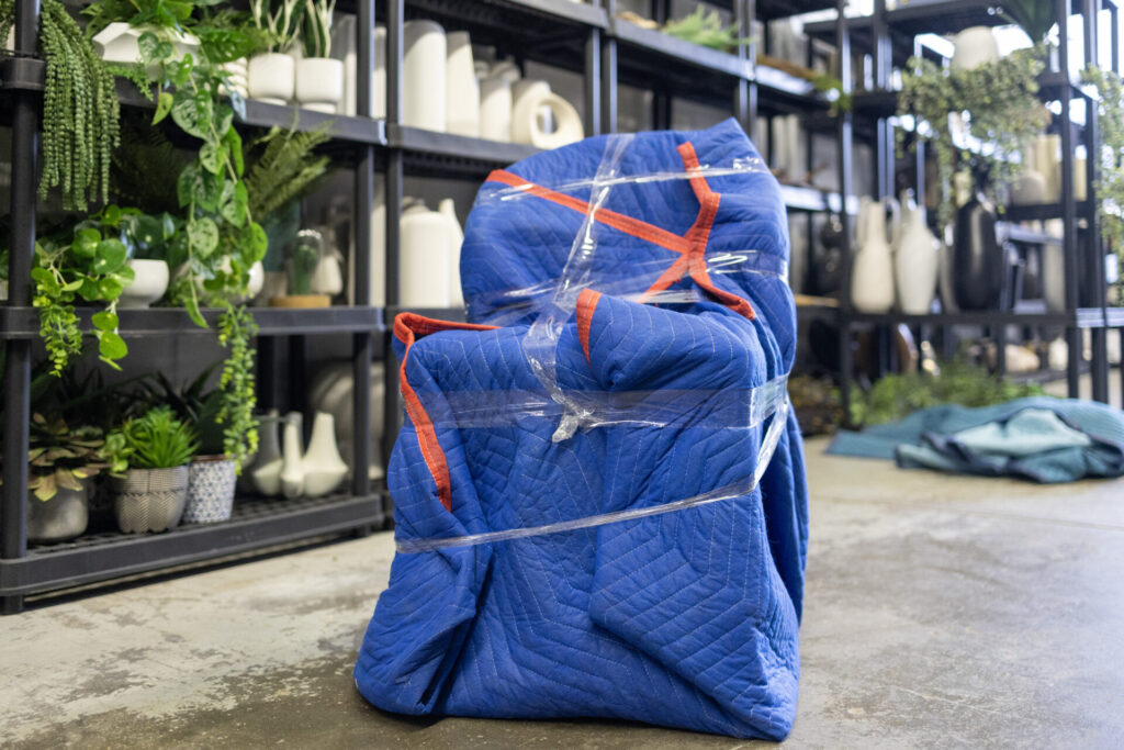 Chair wrapped in blue protective padding and plastic wrap, ready for transport by Toronto movers.