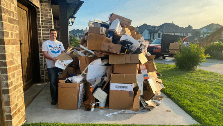 A junk removal worker in a Toronto Unique Moving shirt stands beside a massive pile of cardboard boxes, packaging waste, and discarded household items on a driveway