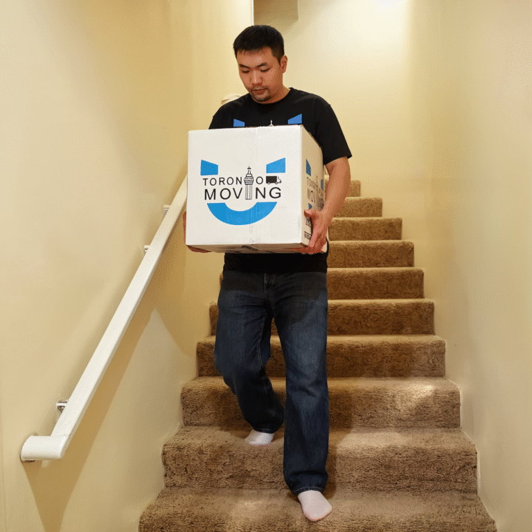 Mover carrying a box downstairs during a basement suite move in Toronto