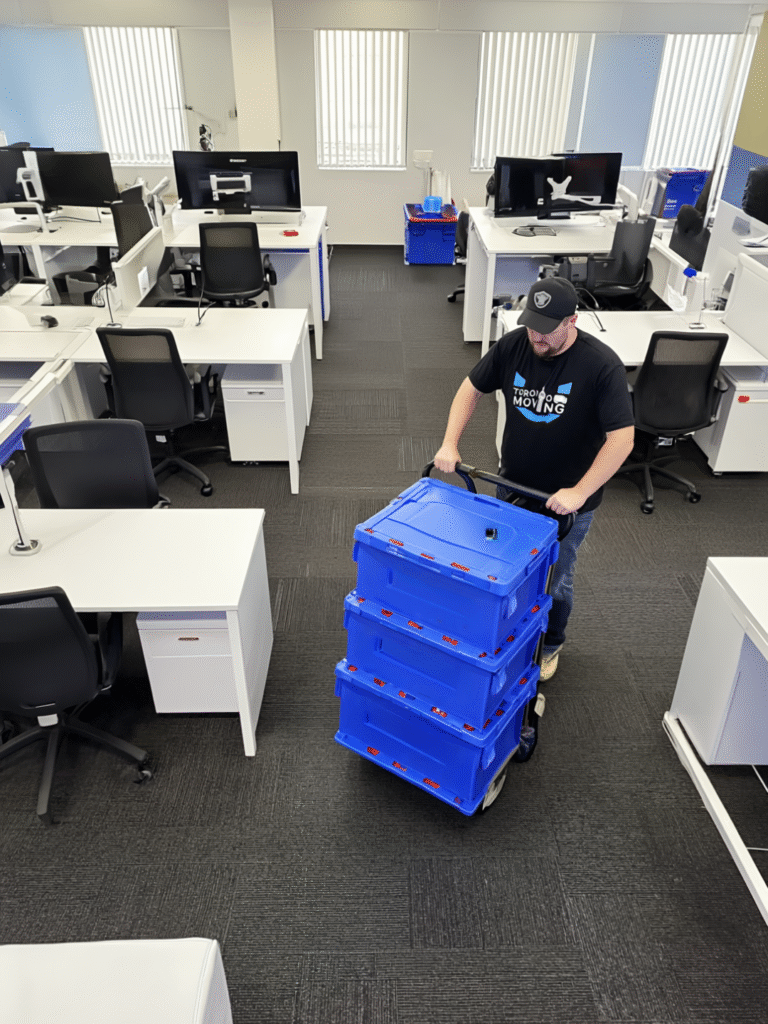 Toronto mover with dolly and blue bins during business relocation in office space