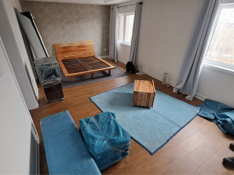Bedroom staged for a Toronto move with moving blankets on the floor and furniture disassembled for safe packing.