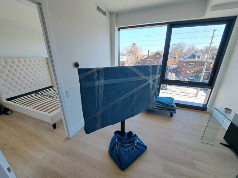 Flat screen TV securely wrapped with moving blankets and tape during Toronto packing services.