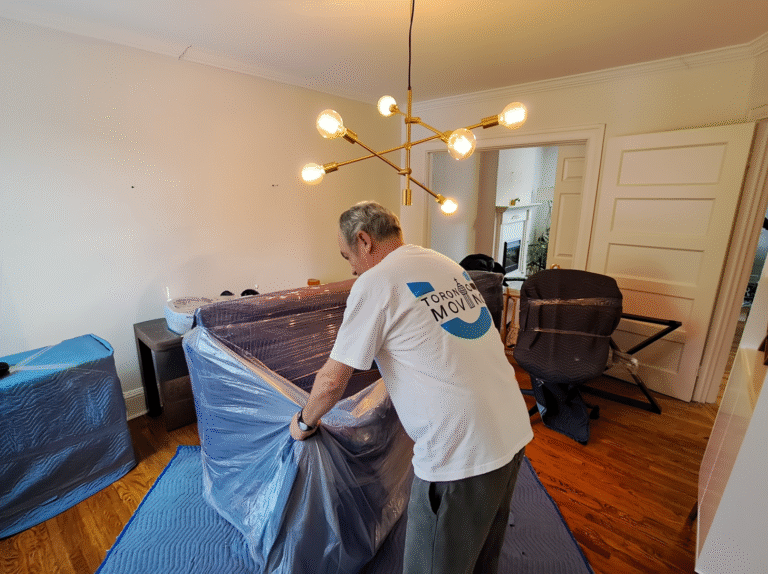 Toronto mover wrapping furniture with plastic and blankets as part of professional packing services.