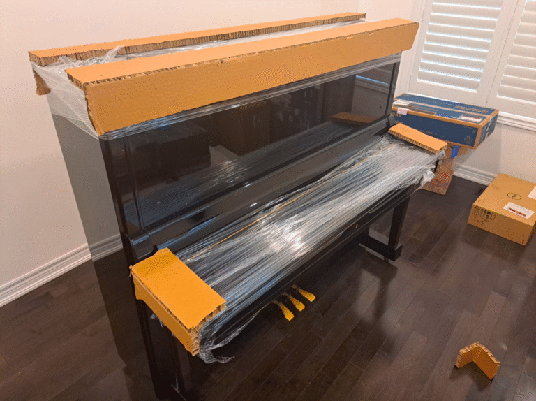 Upright piano in Toronto with cardboard corner protectors and stretch wrap applied by professional piano movers.