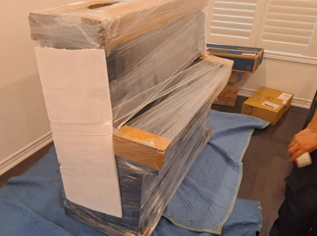 安达搬运在多伦多为三角钢琴进行全毯包裹，蓝色专业毛毯+伸缩膜双保险，全程保护钢琴漆面免受划伤。